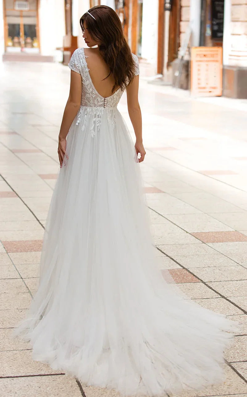 Vestido de novia de tul con cola larga, escote pronunciado y corte en A con apliques